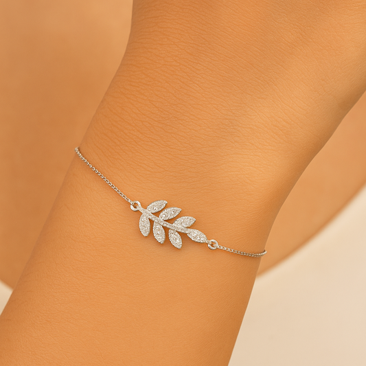 Silver leaf bracelet on a person's wrist against a beige background