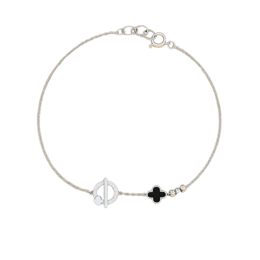 Silver bracelet with black clover charm on a beige background
