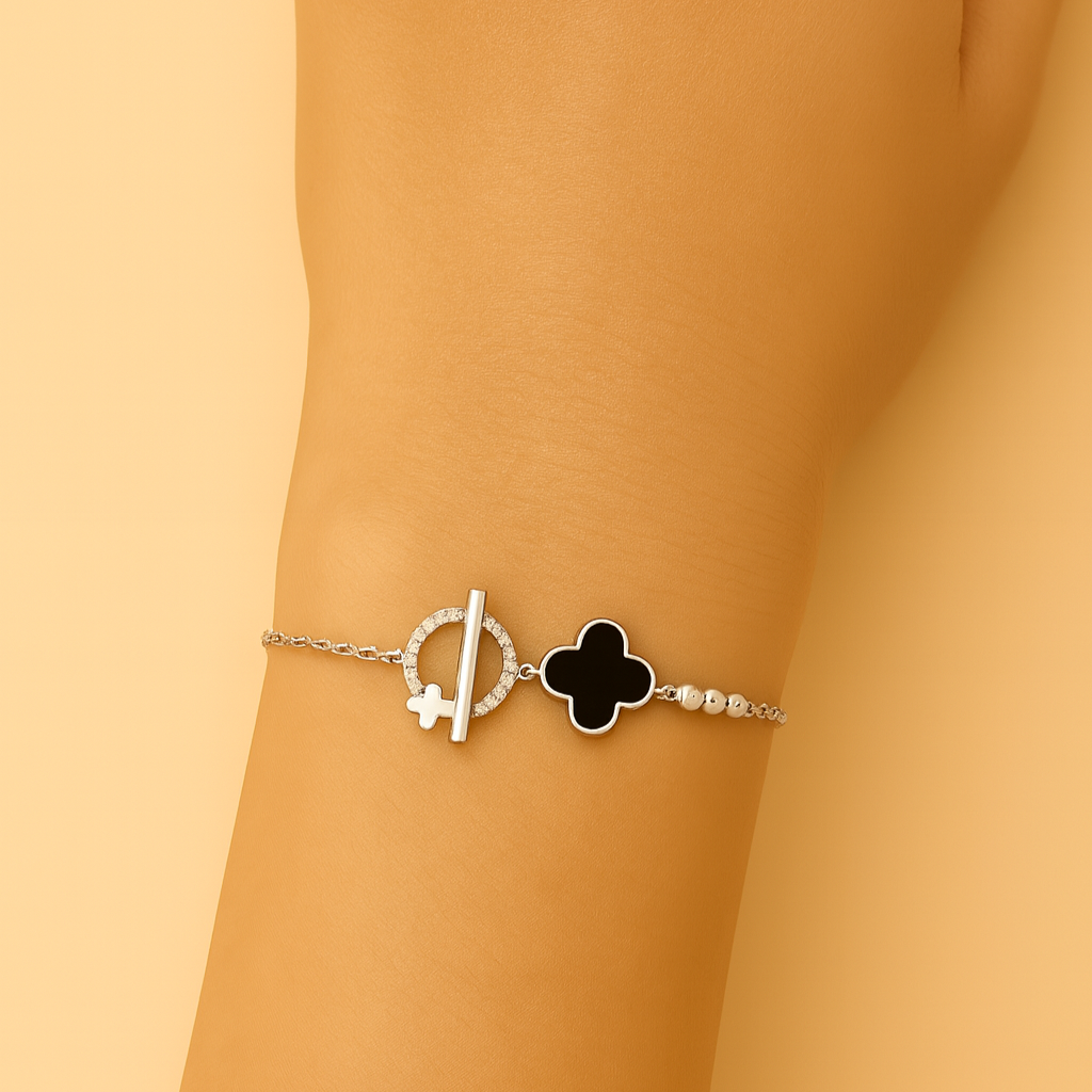 Bracelet with a clover charm on a wrist against a beige background