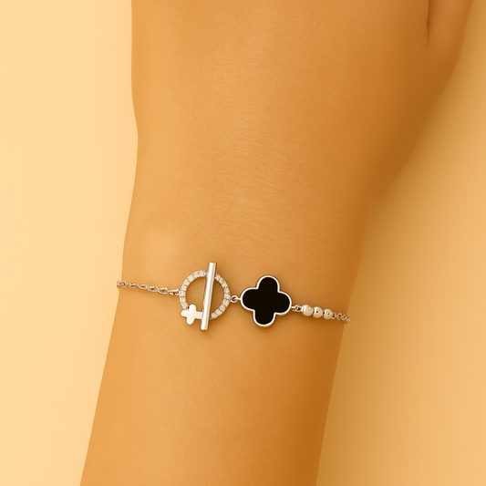 Bracelet with a clover charm on a wrist against a beige background