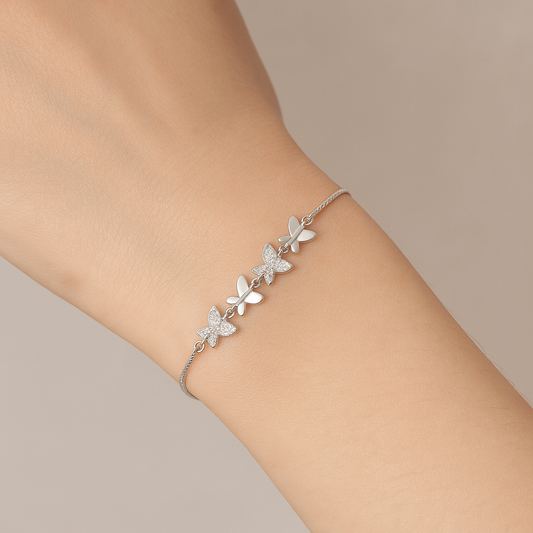 Silver bracelet with butterfly designs on a wrist against a neutral background