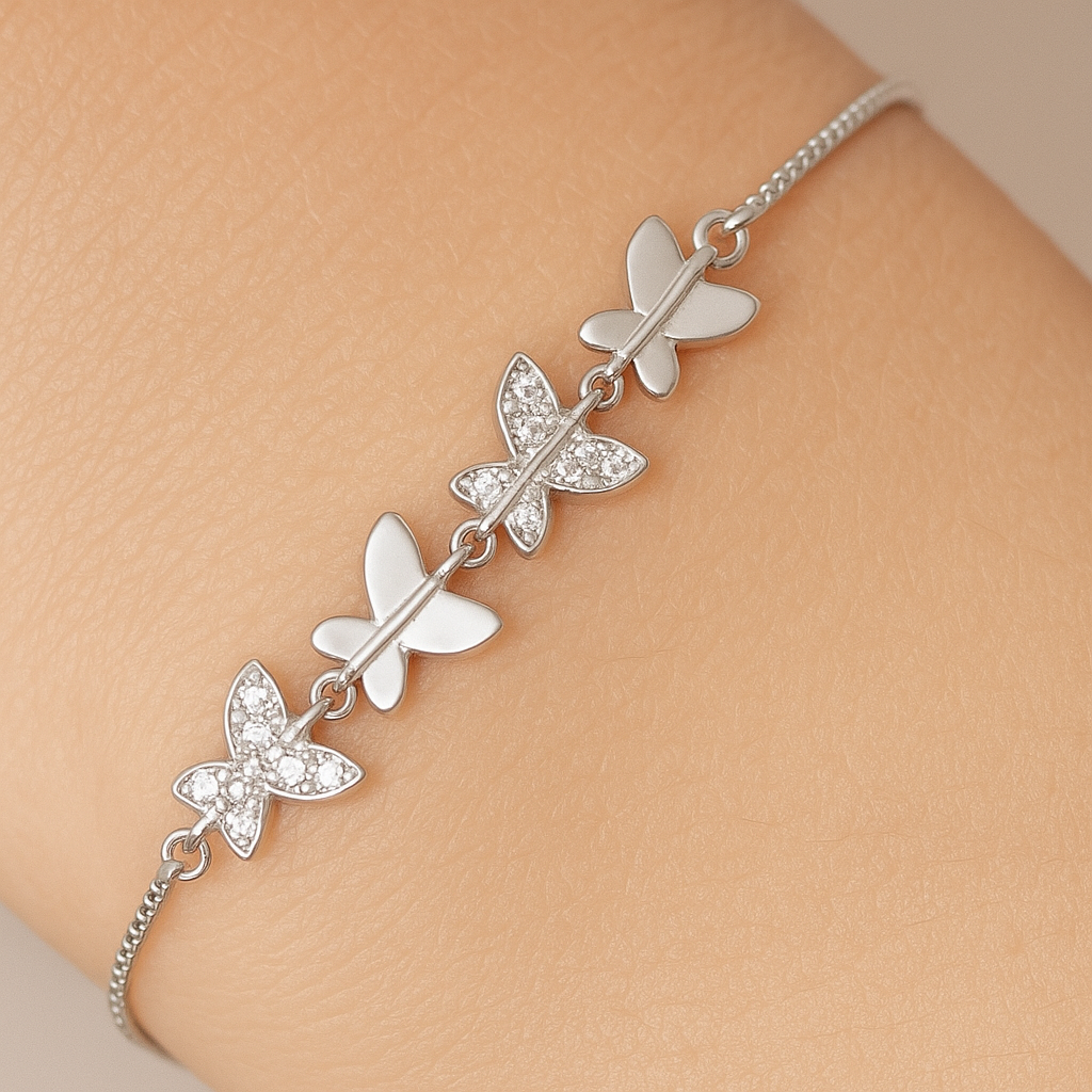 Silver butterfly bracelet on a person's wrist against a beige background