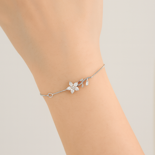 Silver bracelet with floral design on a wrist against a light background
