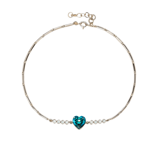 Silver bracelet with a blue heart-shaped gemstone on a beige background