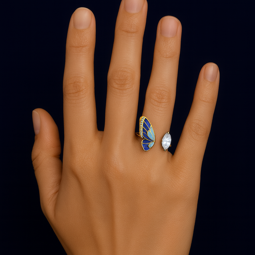 Hand wearing a butterfly-shaped ring with blue wings and gold accents on a black background