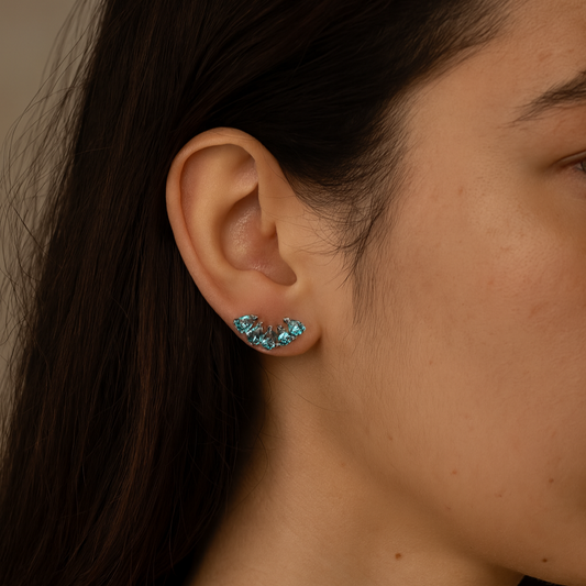 Close-up of an ear wearing a turquoise earring with a neutral background