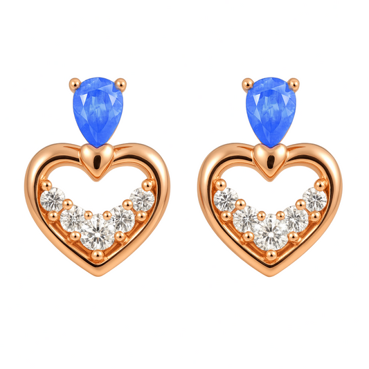Heart-shaped earrings with blue gemstones and rose gold accents on a beige background