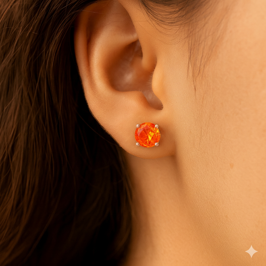 Close-up of an ear wearing a round orange gemstone earring.