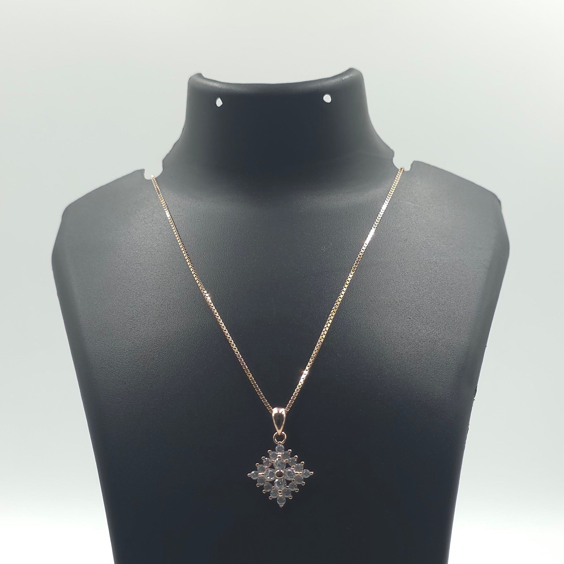 A delicate silver-toned necklace with a snowflake or starburst pendant, displayed on a black jewelry bust against a white background.