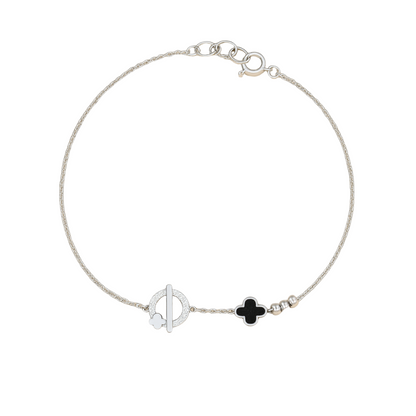 Silver bracelet with black clover charm on a beige background