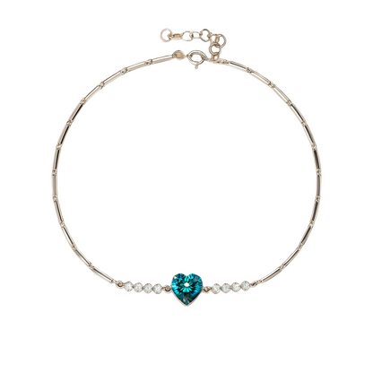 Silver bracelet with a blue heart-shaped gemstone on a beige background