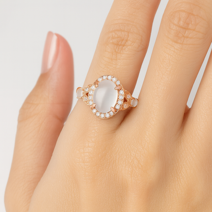 Rose gold ring with a large gemstone on a hand against a light background