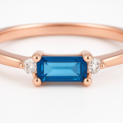 Rose gold ring with a blue gemstone and smaller diamonds on a white background