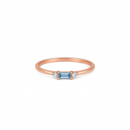 Rose gold ring with a blue gemstone on a white background