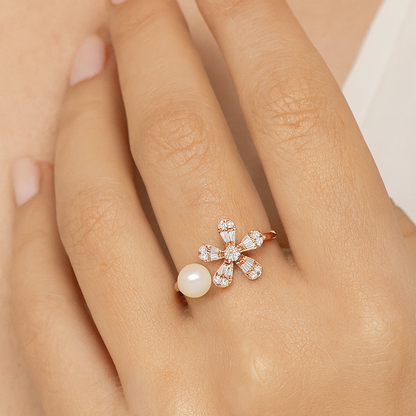 Rose gold ring with a pearl and diamonds on a hand against a neutral background